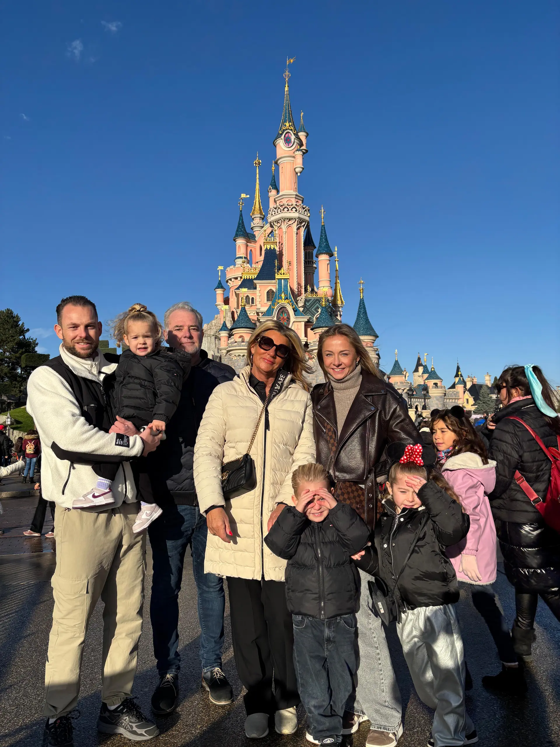 Opa, oma, kinderen en kleinkinderen samen voor het kasteel in het Disneyland Park