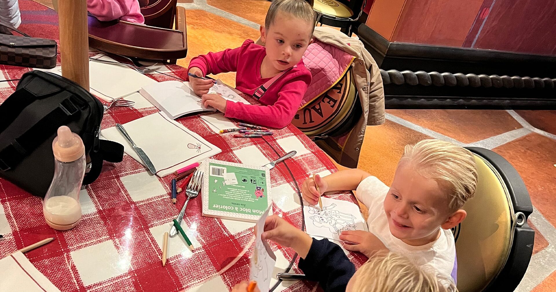 Twee kinderen kleuren aan een tafel in de vorm van een jampotdeksel in Bistrot Chez Rémy